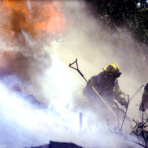 Firefighters cutting a hole in the roof for ventilation.